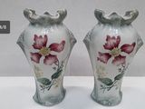 deux vases avec des fleurs peintes dessus, posés sur une table