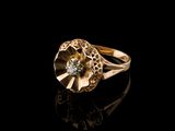 a close up of a gold ring with a diamond on a black surface
