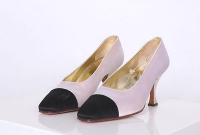 une paire de chaussures roses et noires posées sur une surface blanche
