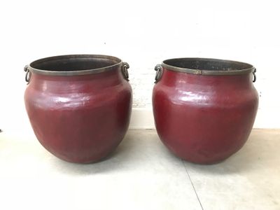 two red pots sitting on the floor next to each other