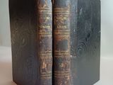 an old pair of books sitting on top of a white table