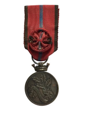 une ancienne médaille avec un ruban rouge sur fond blanc