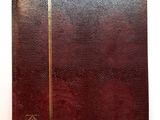 un vieux livre à la couverture marron et aux bords dorés, posé sur une surface blanche