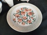 a plate with a flower design on it next to a cup and saucer