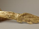 brass eagle figurine next to a bowl of food on a table