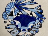 un crabe bleu et blanc sur un carreau orné d'un éventail