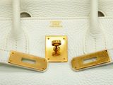 the handle of a white purse with gold hardware on it