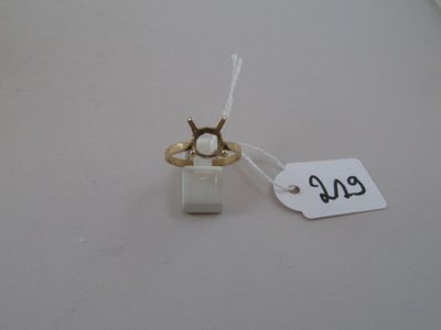 a small white box with a gold ring on top of it