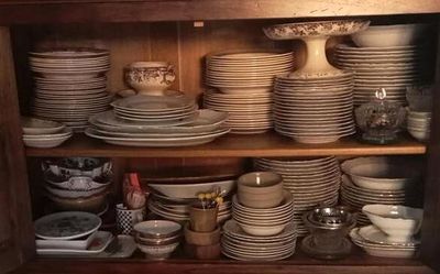 de nombreuses assiettes et bols empilés sur une étagère dans un placard
