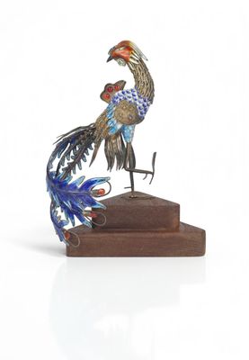 a metal sculpture of a bird on a wooden base