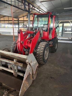 a red tractor that is parked inside of a building