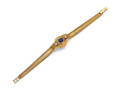 un gros plan d'une montre-bracelet en or sertie d'une pierre bleue