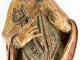 an old statue of a man with a beard holding a cross