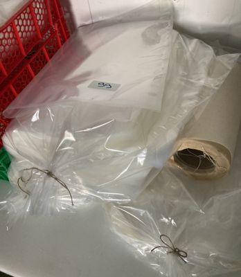 un panier rouge contenant un rouleau de papier toilette à côté d'un autre rouleau de papier toilette