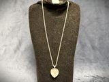 a necklace with a heart shaped pendant on a mannequin