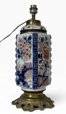 un vase bleu et blanc posé sur un socle surmonté d'une lampe