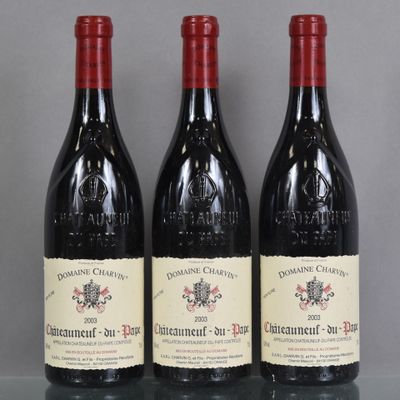 three bottles of red wine are lined up on a glass table