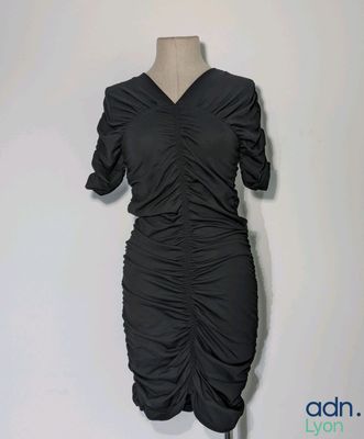 La robe est noire et présente un motif froncé.