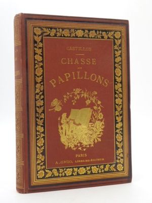 un livre rouge avec des lettres dorées posé sur une surface blanche
