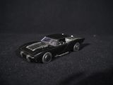 a black toy car that is sitting on a black surface