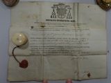 someone is holding a piece of paper with a wax seal on it