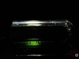dans l'obscurité, la lumière verte brille sur un morceau de verre