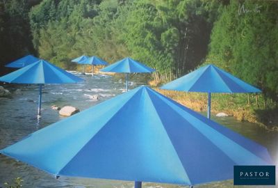 many blue umbrellas sitting on the side of a river
