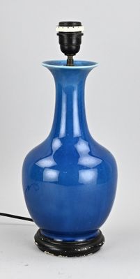 un vase bleu avec un socle noir et une bande blanche sur le haut