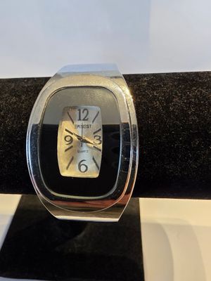 montre argentée et noire posée sur une surface à carreaux noirs et blancs