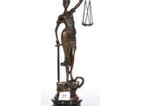 une statue en bronze représentant une femme tenant une épée et une balance