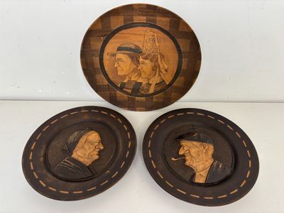 trois assiettes en bois sur lesquelles sont sculptées des figures d'hommes et de femmes