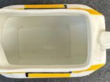 a white and yellow bowl with a handle on the floor