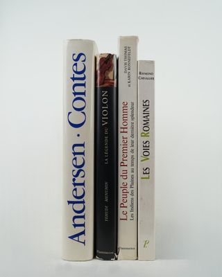 three books sitting on top of each other on a white surface