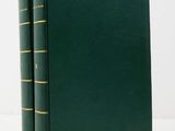 two green books sitting on top of each other on a white surface