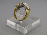 une photo d'une bague en or et en argent posée sur un socle transparent