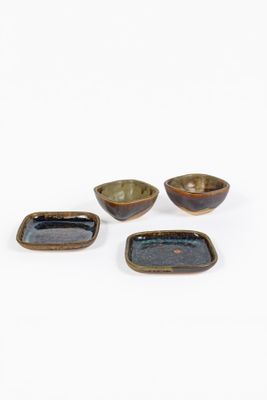 trois petits bols et un grand bol sont posés sur une surface blanche