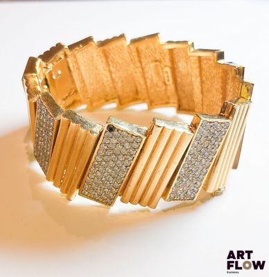 un bracelet en or serti de diamants, posé sur un fond blanc