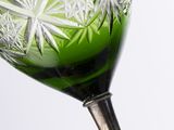 a green wine glass with a silver stem on a white background