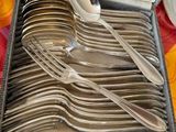 des couverts rangés dans un coffret posé sur une table recouverte d'une nappe colorée