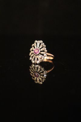 a close up of a gold ring with a pink stone in the center