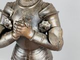 a silver statue of a man in armor holding a bird