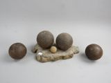 trois boules en bois et une boule en bois posée sur un rocher, le tout sur une surface blanche