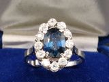 gros plan d'une bague avec une pierre bleue entourée de diamants