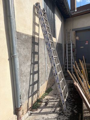 a ladder leaning up against a building next to a pile of wood