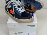 une paire de baskets bleues et orange posée sur une boîte blanche