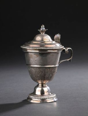 une coupe ancienne en argent avec un couvercle, posée sur une surface noire