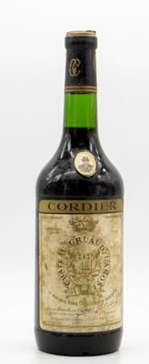 une vieille bouteille de Cordier est posée sur une surface blanche