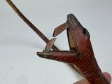 a hand holding a small metal object with a long cord