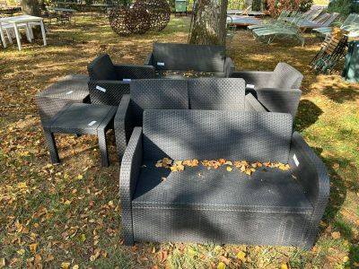 un canapé en osier noir posé au milieu de la pelouse