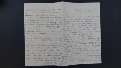 une vieille lettre manuscrite, posée sur un bout de papier, sur une table